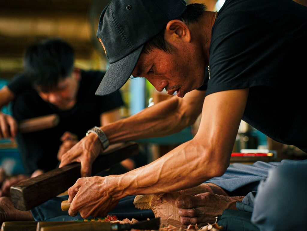 Artisan at work carving and painting wood at Lang Cui Lu - Driftwood Village in Hoi An, Vietnam.