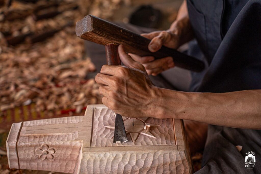 Master artisan’s hands carving driftwood at Lang Cui Lu workshop.